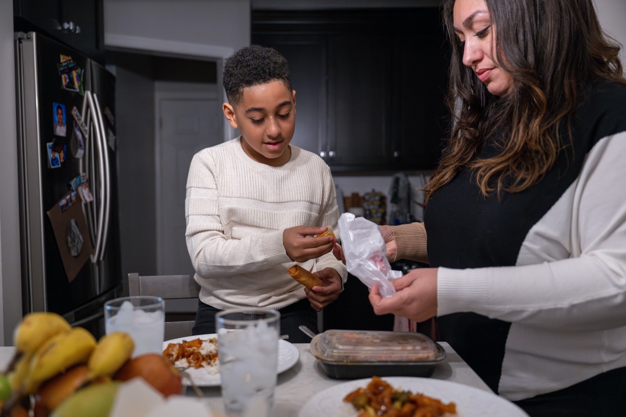 a woman and a boy in a kitchen making food together