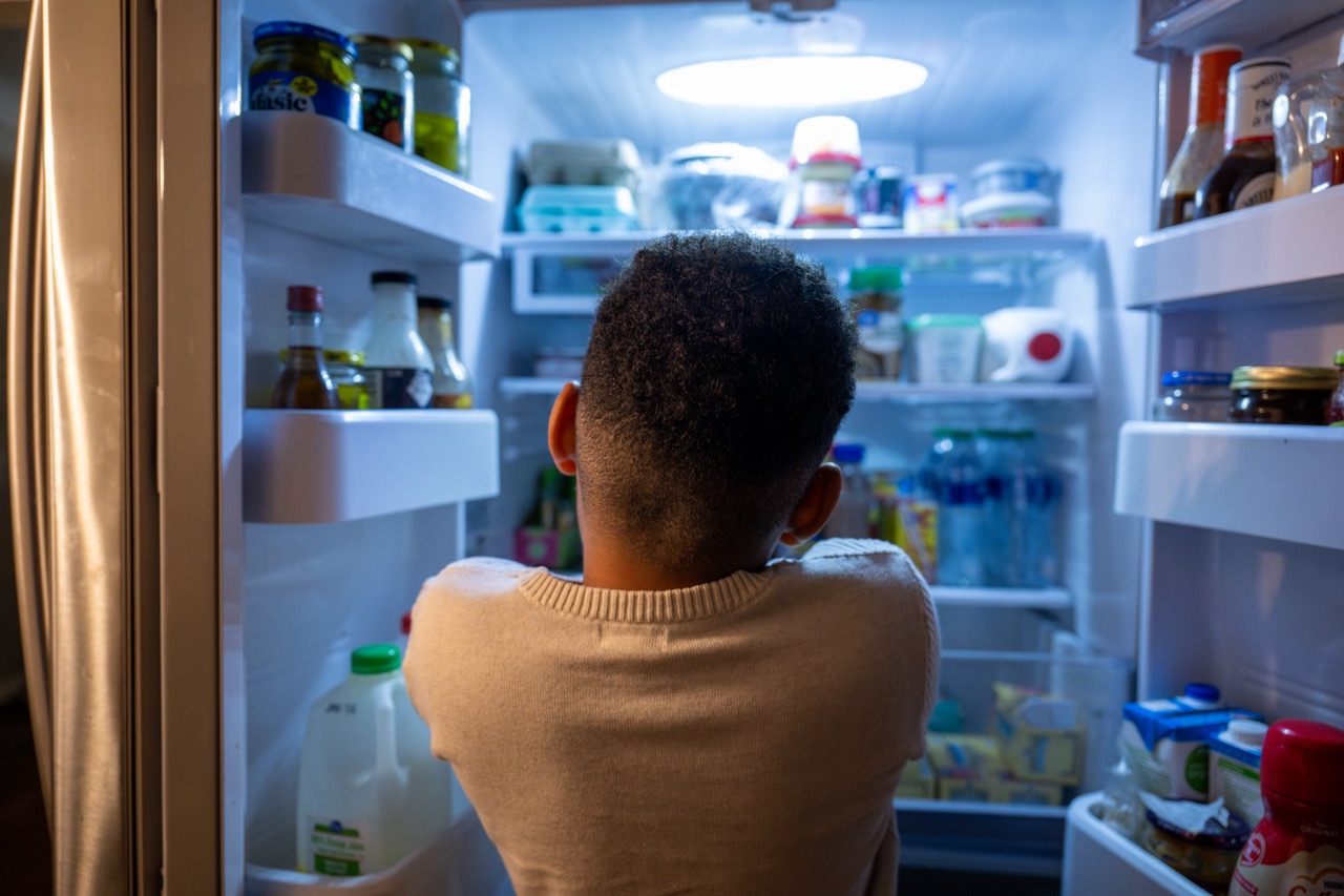 a young boy looks in fridge