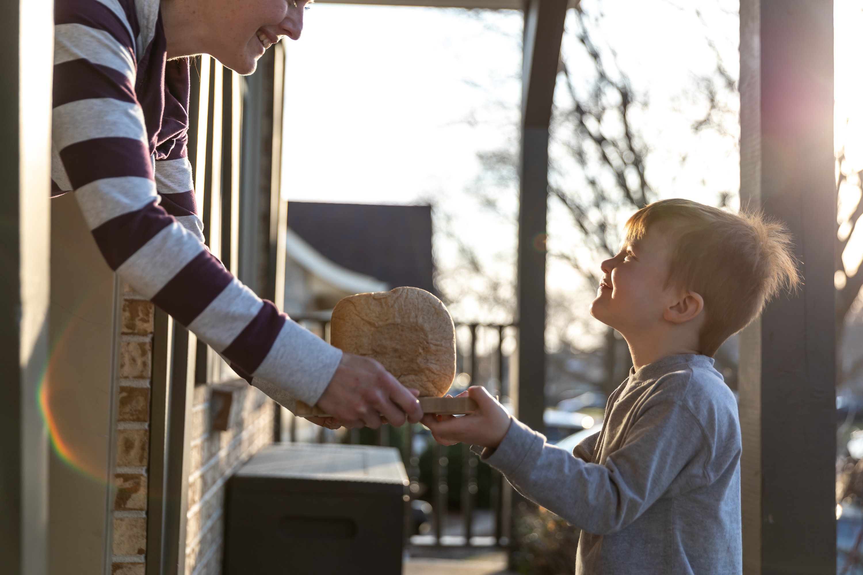 young cute redhead kid bringing homemade bread to neighbor's door