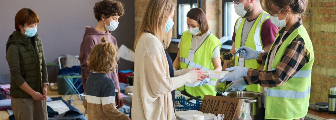 group of young volunteers in masks and gloves spreading cooked food