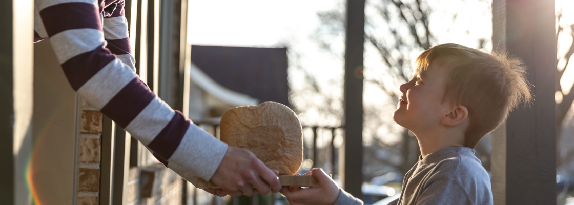 young cute redhead kid bringing homemade bread to neighbor's door