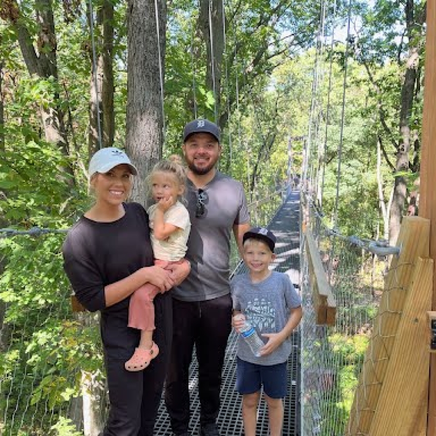 a family stands together smiling in the forest