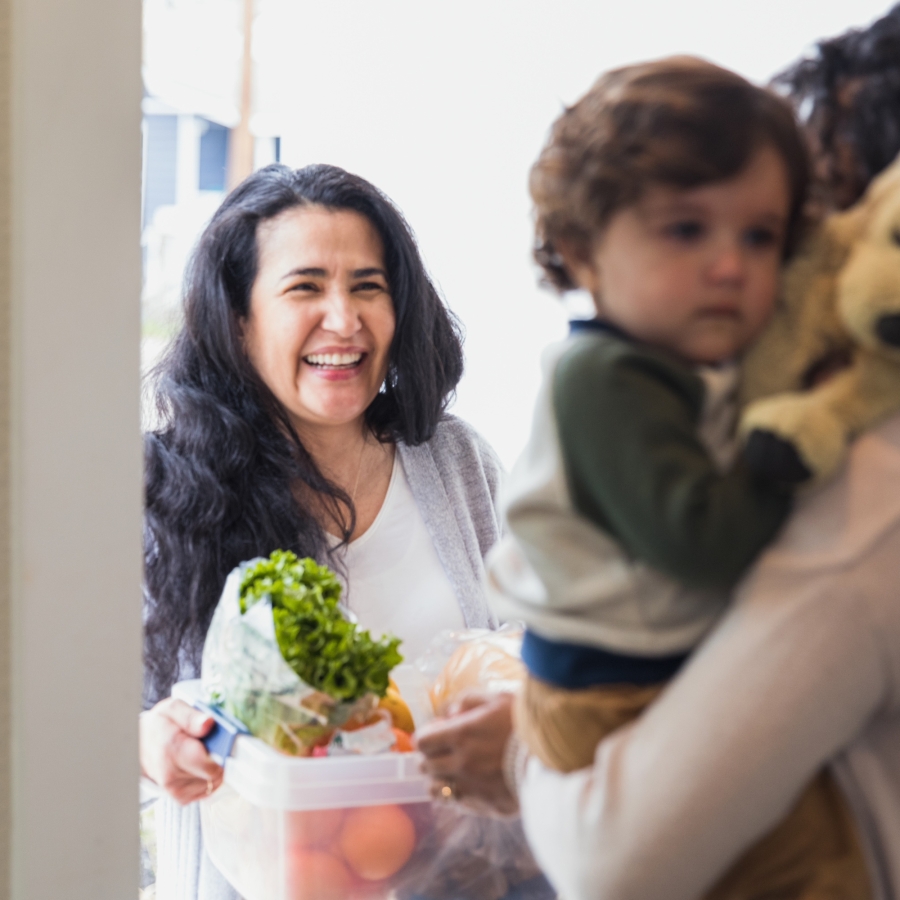 mature woman gives fresh produce to young adult daughter